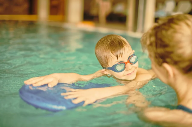 Child taking swimming lessons in an indoor pool.